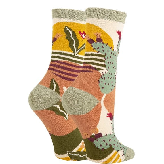 Women's calf socks patterned with geometric cacti and desert plants in a mellow green, yellow and orange color scheme.