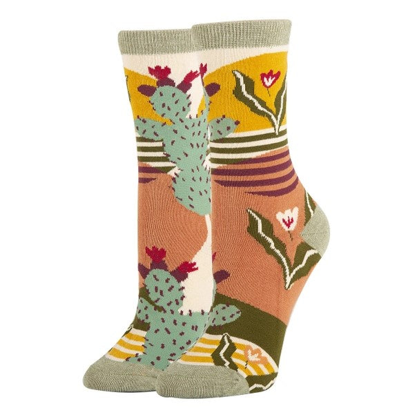 Women's calf socks patterned with geometric cacti and desert plants in a mellow green, yellow and orange color scheme.