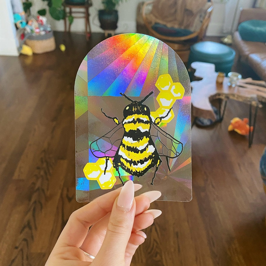 Hand holding prism sticker decal with a bee