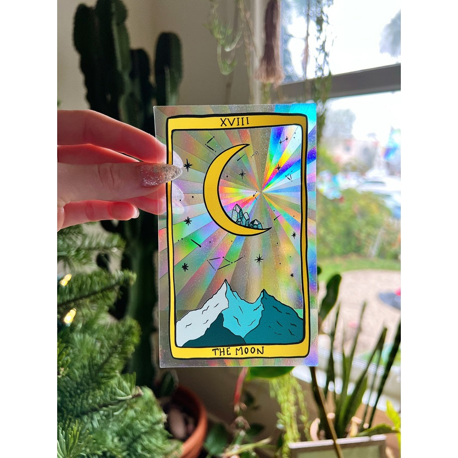 hand holding holographic sticker with mountains and moon shaped like a tarot card
