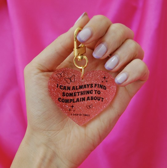 Hand holding heart glittery key chain with quote "I can always find something to complain about"