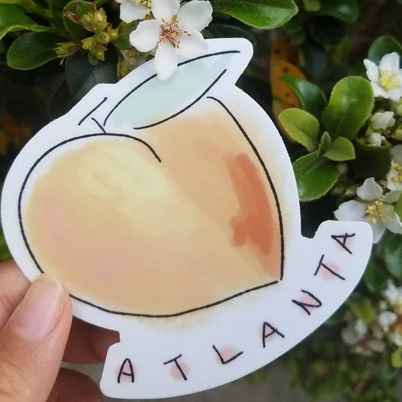 Hand holding a peach sticker that says Atlanta