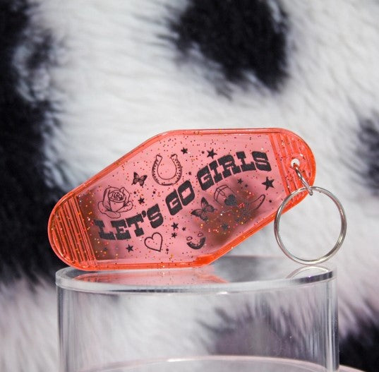 Pink See-thru glittery key chain with quote "Let's Go Girls" and roses, hearts, cowboy boots, butterflies, and other symbols surrounding quote