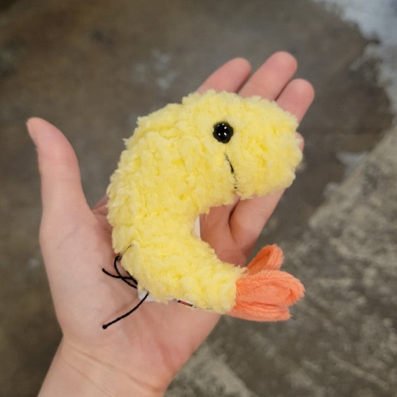 Hand holding small plush shrimp toy