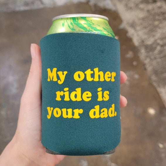 Hand holding can koozie inside can with the phrase "my other ride is your dad"