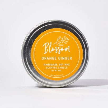 Silver Tin candle with orange sticker showcasing the Orange Ginger scent