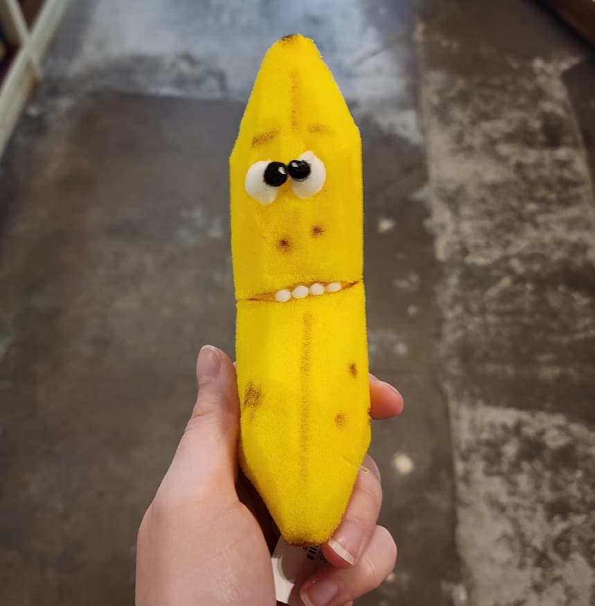 Hand holding yellow foam puppet shaped like a banana with eyes