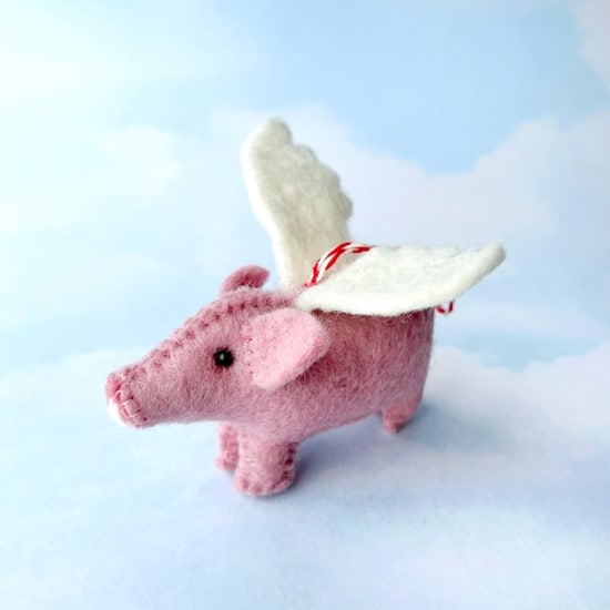 pink pig with white wings attached to a red and white striped string